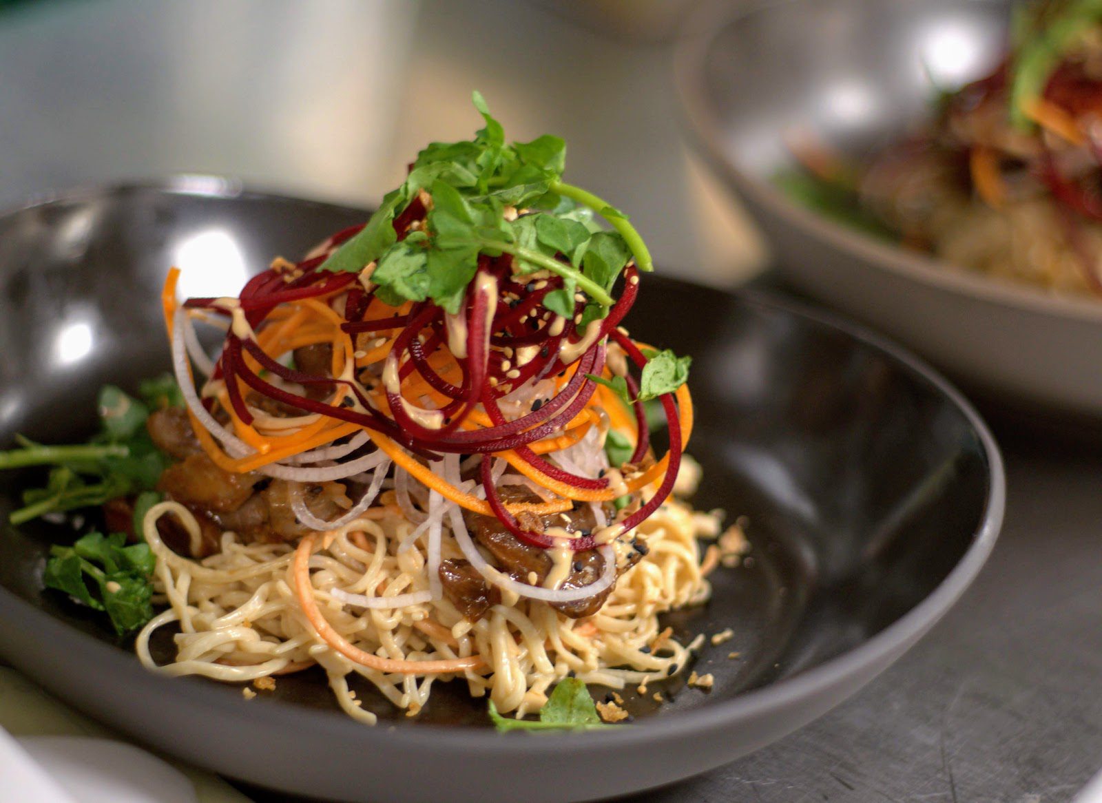 A delicious Asian-inspired noodle dish in a black bowl.